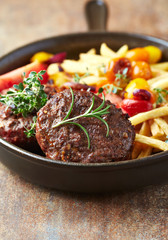 Fried hamburger steaks with tomatoes and french fries. Rustic background. 