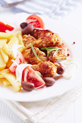 Spicy Chicken Wings with french fries, tomatoes and kalamata olives. Bright background. 