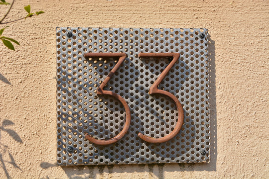 A house number plaque, showing the number thirty three (33)