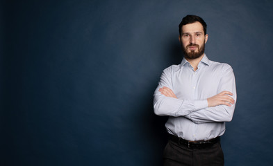Obraz premium Casual businessman with arms crossed on blue background. 