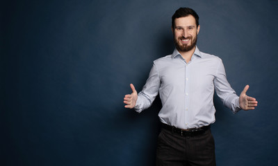 Happy bearded businessman looking at camera on blue background with copy space.