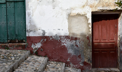 Very damaged house facade with a red and a green door