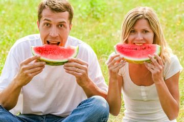 happy couple in love eating watermelon outdoors in summer park