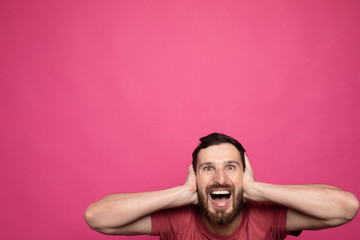 Happy glad young bearded man shoked with great news on pink background.