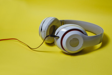 Naklejka premium White cordless audio headphones on a yellow background.