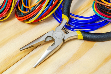 Pliers tool and wires for electrician closeup service repairing concept on wooden boards