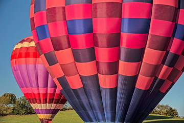 Close up colorful hot air balloons ready to fly in a clear blue sky.