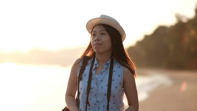 Asian woman walking along beach and take a photo with her camera.