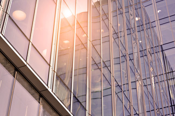 Obraz premium Sun rays light effects on urban buildings in sunset. Modern office building detail, glass surface with sunlight. Business background. 