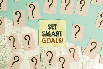 Text sign showing Set Smart Goals. Business photo text list to clarify your ideas focus efforts use time wisely Scribbled and crumbling papers with thick cardboard above wooden table