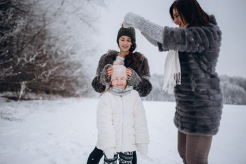 happy family mother and child daughter having fun, playing at winter walk outdoors