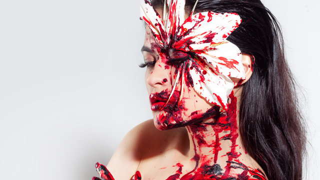 Blood Lily, scary and sexy Halloween look. Beautiful young brunette girl on white background