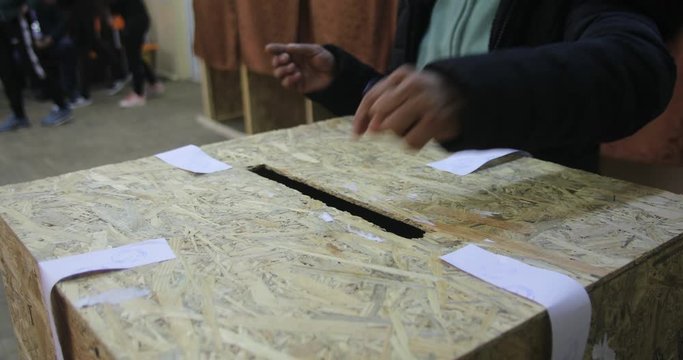 Close up 4K footage of an unidentifiable person casting a ballot during elections, at a polling station.