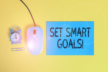 Word writing text Set Smart Goals. Business photo showcasing list to clarify your ideas focus efforts use time wisely Blank paper sheet alarm clock clip wire mouse gadget colored background
