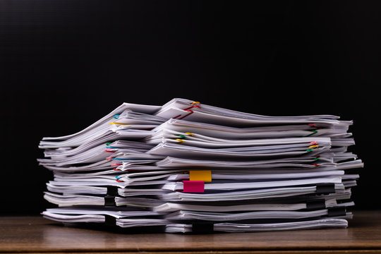 Stack overload document report paper with colorful paperclip on black background.