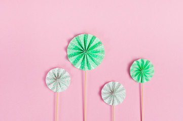 Round cake toppers on wooden sticks on pink background