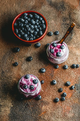 Homemade blueberry yogurt in glass bowls, healthy breakfast, selective focus. Old wood background
