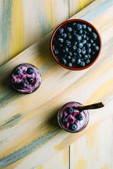 Obraz na płótnie Canvas Homemade blueberry yogurt in glass bowls, healthy breakfast, selective focus. Old wood background