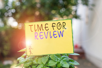 Writing note showing Time For Review. Business concept for review of a system or situation in its formal examination Plain paper attached to stick and placed in the grassy land