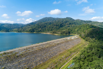 Aerial Drone shot bird eye view Blue sky with rainforest and road around dam.