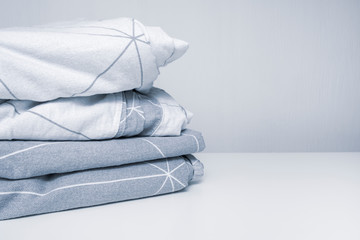 A stack of cozy home textile in shades of gray bed linen, bedding with copy space