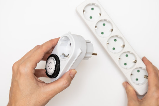 24 Hour 7 days a week mains plug timer switch european socket for energy and money saving in hands, electrical power socket on background