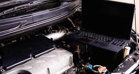 Laptop computer on car mechanic engine for service