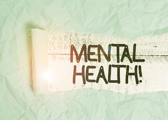 Text sign showing Mental Health. Business photo text demonstratings condition regard to their psychological well being Cardboard which is torn in the middle placed above a wooden classic table