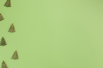 Small wooden christmas trees on green background. Christmas, winter concept. Flat lay, top view, copy space.