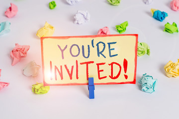 Handwriting text You Re Invited. Conceptual photo make a polite friendly request to someone go somewhere Colored crumpled papers empty reminder white floor background clothespin