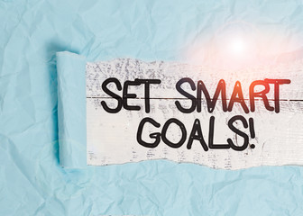 Text sign showing Set Smart Goals. Business photo text list to clarify your ideas focus efforts use time wisely Cardboard which is torn in the middle placed above a wooden classic table