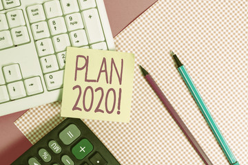 Writing note showing Plan 2020. Business concept for detailed proposal doing achieving something next year Note paper stick to keyboard near colored gift wrap on table