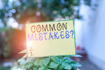 Writing note showing Common Mistakes Question. Business concept for repeat act or judgement misguided making something wrong Plain paper attached to stick and placed in the grassy land