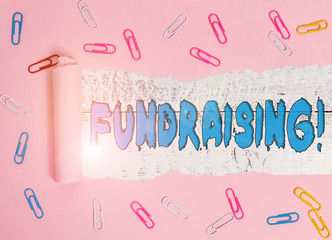 Conceptual hand writing showing Fundraising. Concept meaning seeking to generate financial support for charity or cause Paper clip and torn cardboard on wood classic table backdrop