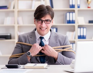 Businessman tied up with rope in office