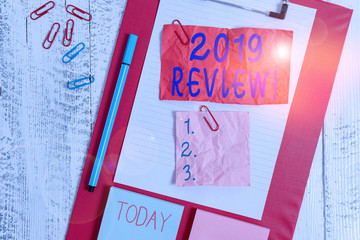 Text sign showing 2019 Review. Business photo text remembering past year events main actions or good shows Clipboard sheet crushed sticky note clip notepads marker wooden background