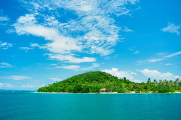 A beach with large stones, the sea and green hills.