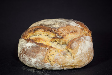 Loaf (or miche) of French sourdough, called as well as Pain de campagne, on display isolated on a black background. Pain de Campagne is a typical French huge loaf of bread abiding by traditional codes