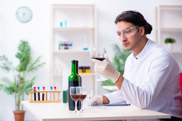 Male chemist examining wine samples at lab