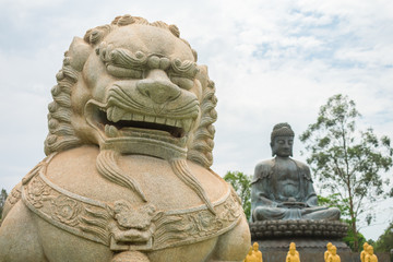 Guardian Lion statue and Great Amitabha Buddha statue in the background at Chen Tien Buddhist Temple in Foz do Iguacu, Brazil