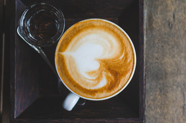 close up coffee top view on wood background with coffee bubble foam pattern and texture in white cup looking and feel so delicious on glasses table in coffee shop.