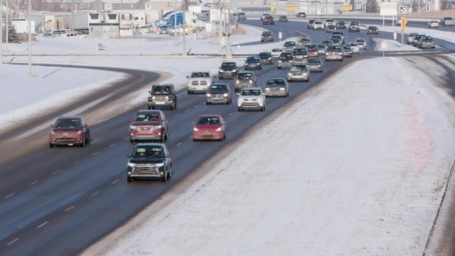 Cold vehicles slowly advance through suburban intersection in winter