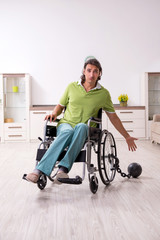 Young male invalid in wheel-chair suffering at home