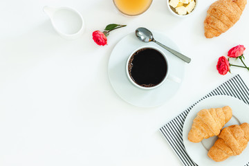 Morning breakfast coffee and croissant, butter, orange juice and flowers on white background. Flat lay, top view