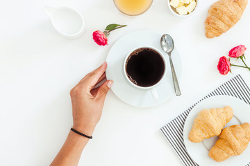 Morning breakfast coffee and croissant, butter, orange juice and flowers on white background. Flat lay, top view
