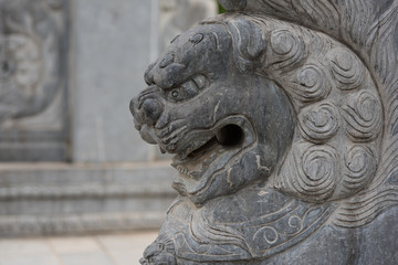 Fototapeta na wymiar Oriental stone lion closeup on stone pillar