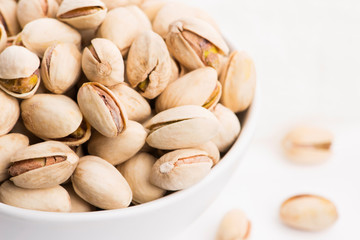 Bowl of roasted pistachios on a white background