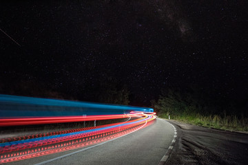 Long exposure photo of colorful car light trails in the night with stars in the background.