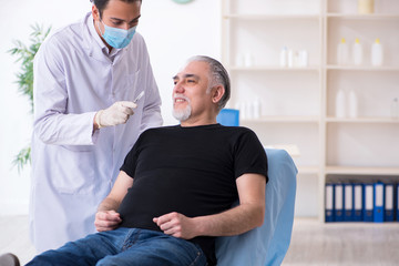 Fototapeta premium Old man visiting young doctor for plastic surgery