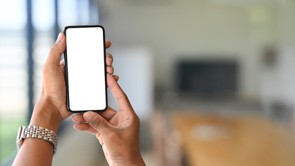 Smartphone on hands with empty screen and meeting room blur background.